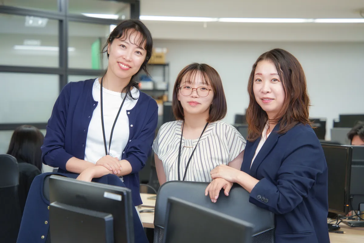 オフィスで並んで笑顔を見せる女性社員