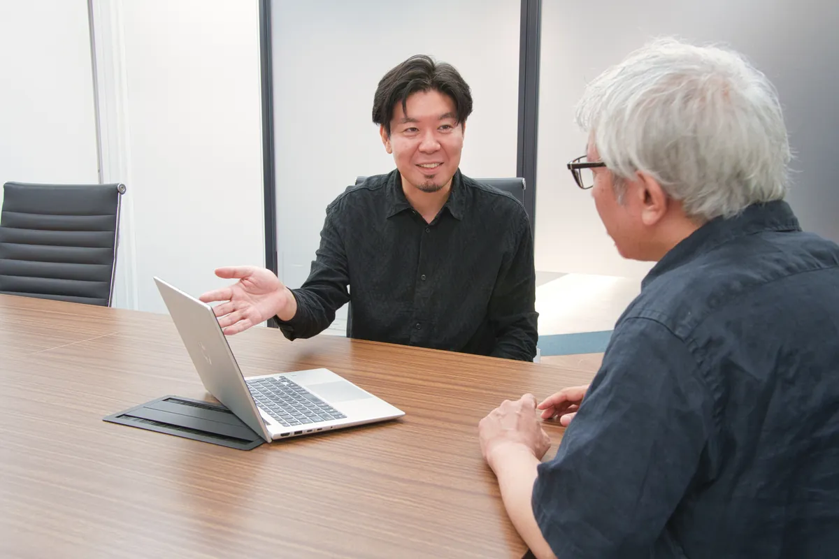 テーブルを挟んで打ち合わせをする社員
